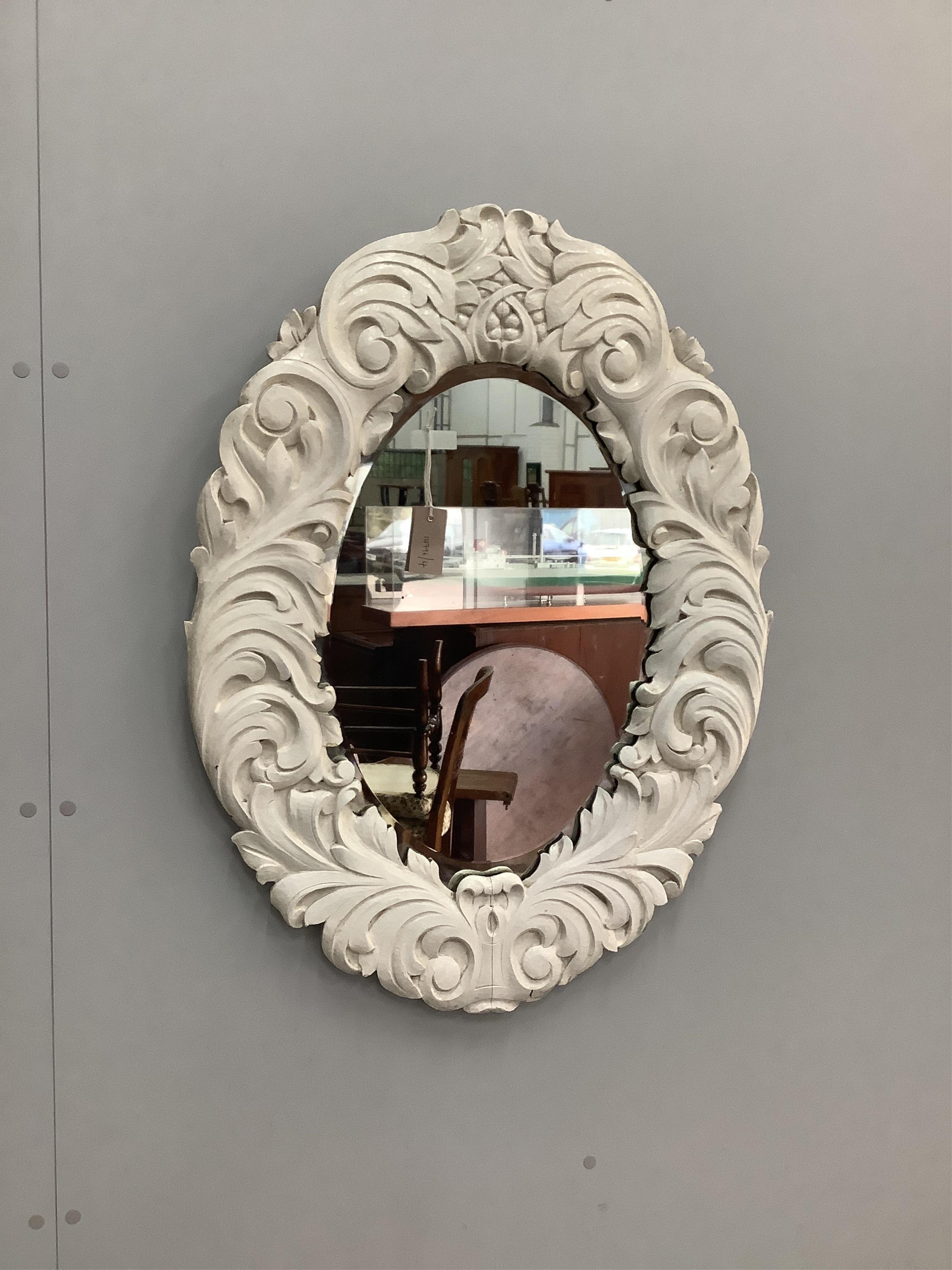 A Victorian style painted oval carved wood wall mirror, width 64cm, height 86cm. Condition - fair